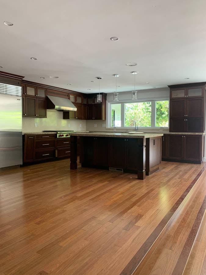 newly remodeled kitchen with kitchen island with brown wood countertops and brown wood laminate flooring